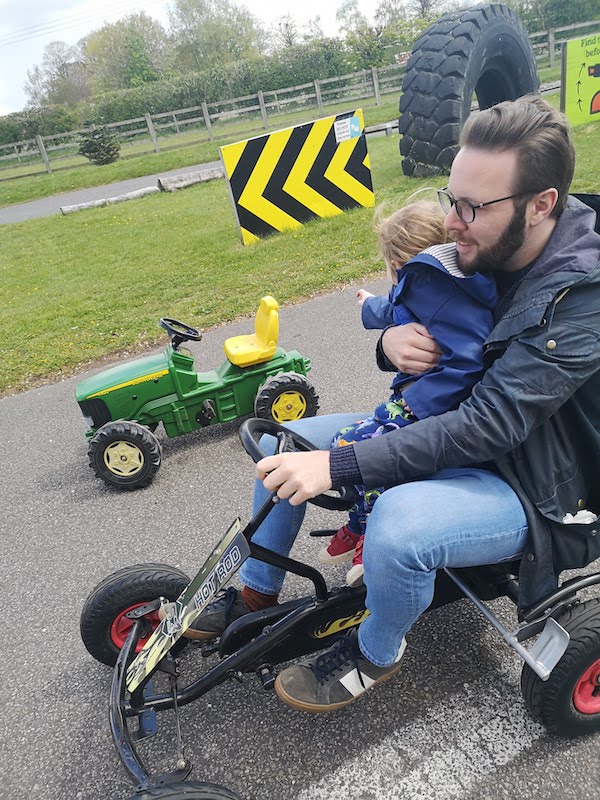 Riding in a go-kart clutching a toddler